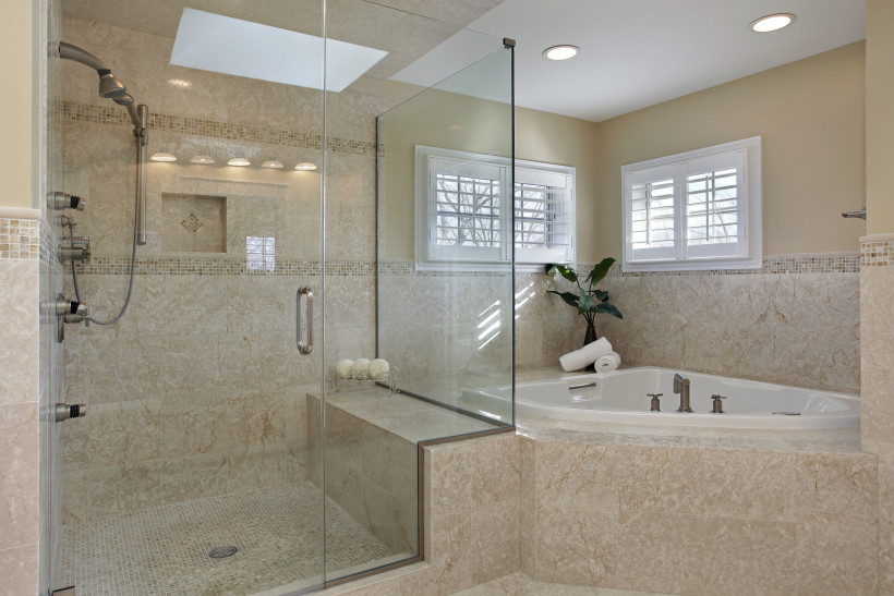 Modern master bathroom with large glass framed shower and a tiled edge ...