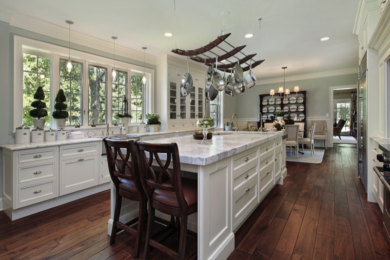 This is stunning example of a white kitchen with a large white granite island.